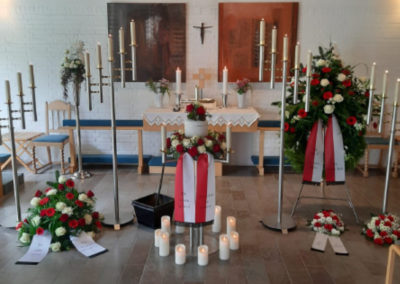 Bestattung: eine Urnenaufbahrung mit Blumen und Kerzen