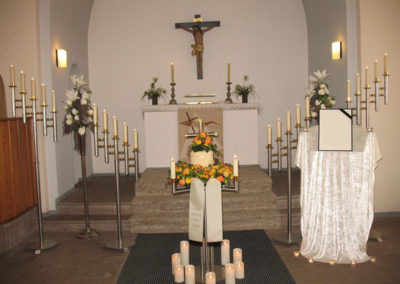 Bestattung: eine Urnenaufbahrung mit Blumen und vielen Kerzen