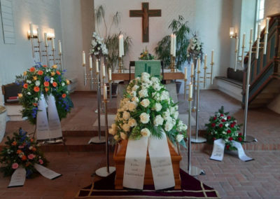 Bestattung: eine Sargaufbahrung mit Blumen und Kerzen
